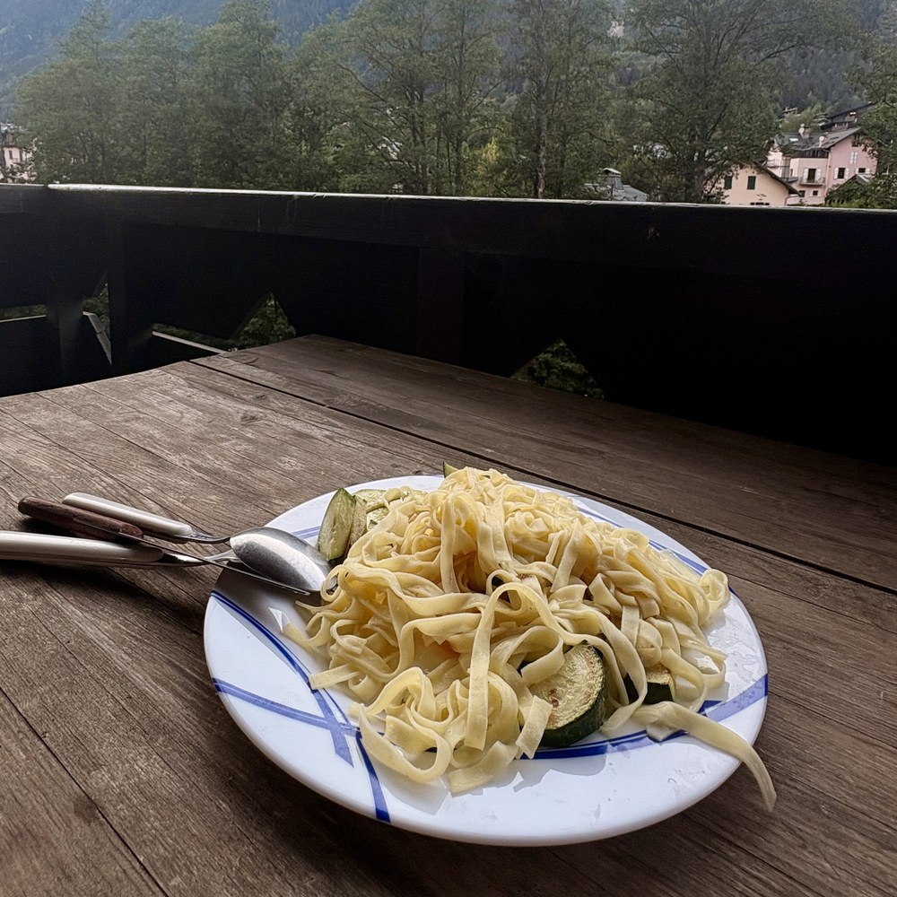 Assiette de tagliatelles aux courgettes sur un balcon, face aux aiguilles de Chamonix au crépuscule